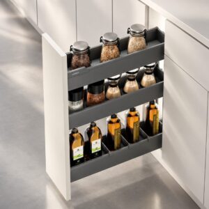 Close-up view of a pull out spice rack with tiered storage, adjustable dividers, and organized pantry jars.