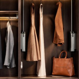 Pull-down closet rod installed in a luxury custom closet with hanging garments and integrated storage